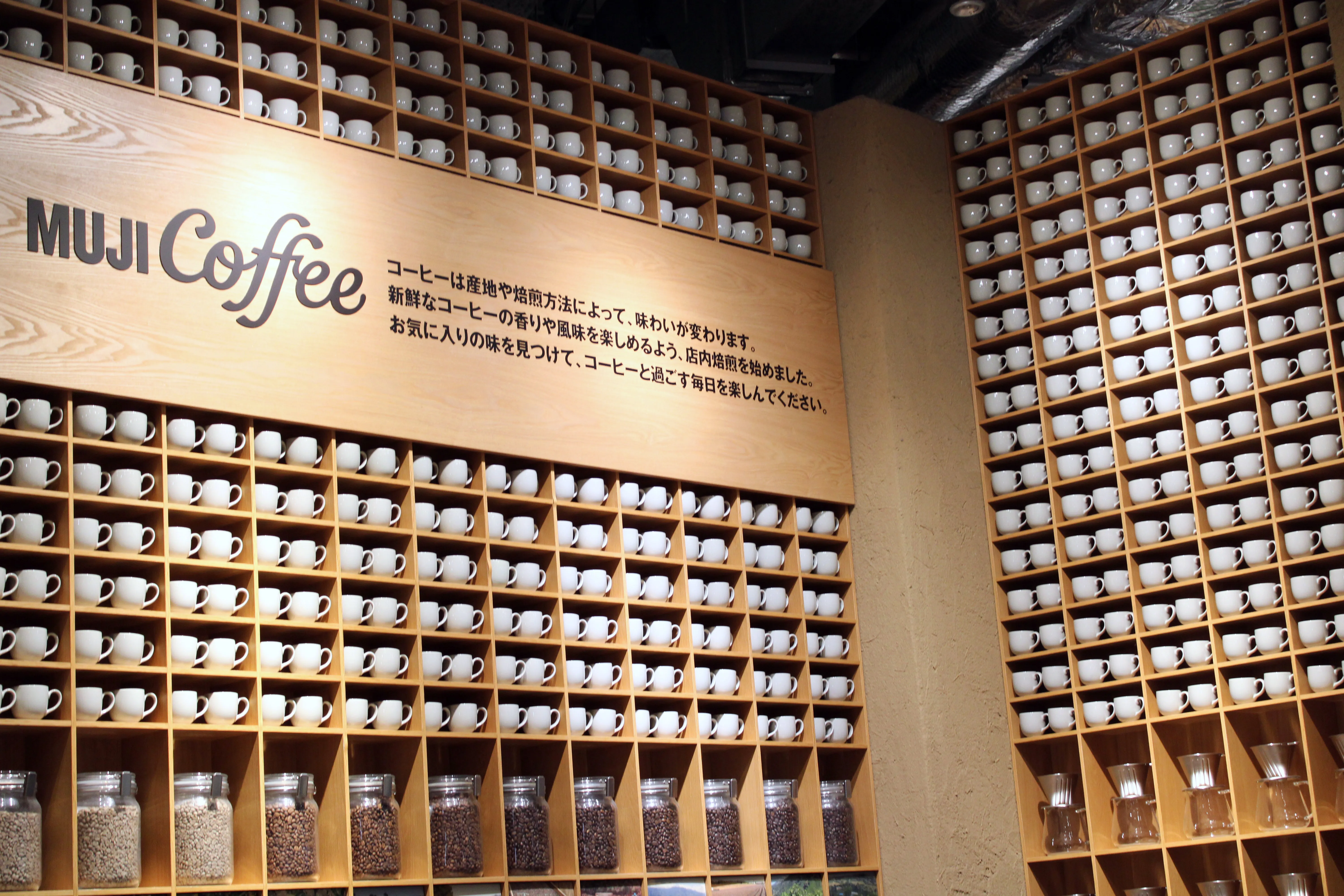 Muji&#x27;s big walls lined to the brim with coffee cups with a sign saying "Muji Coffee" and a bunch of Japanese I can only read small parts of like the three times it says "koohii" which means coffee if that&#x27;s not obvious
